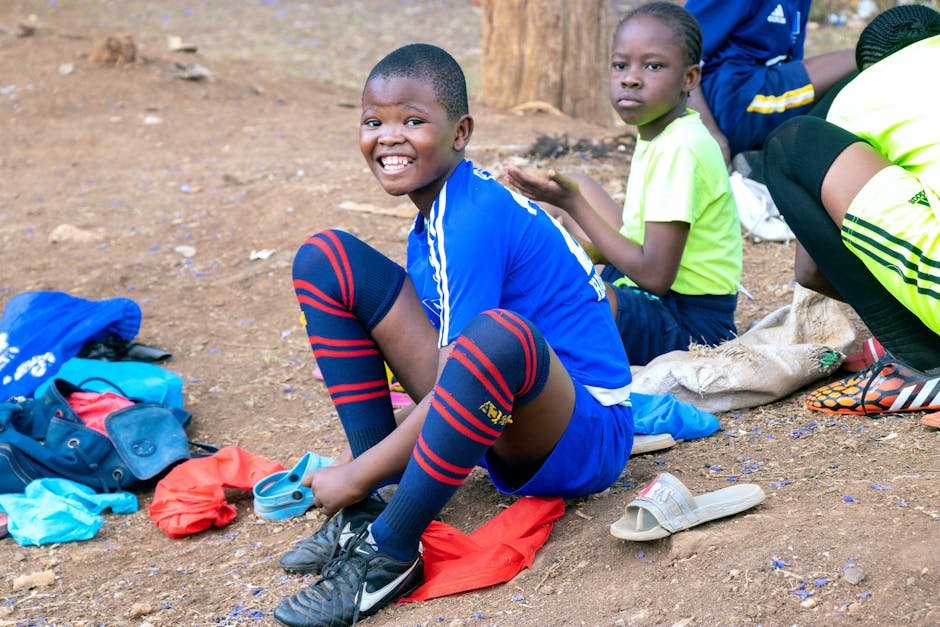 Two boys on a dirt road wearing vibrant sportswear and smiling.