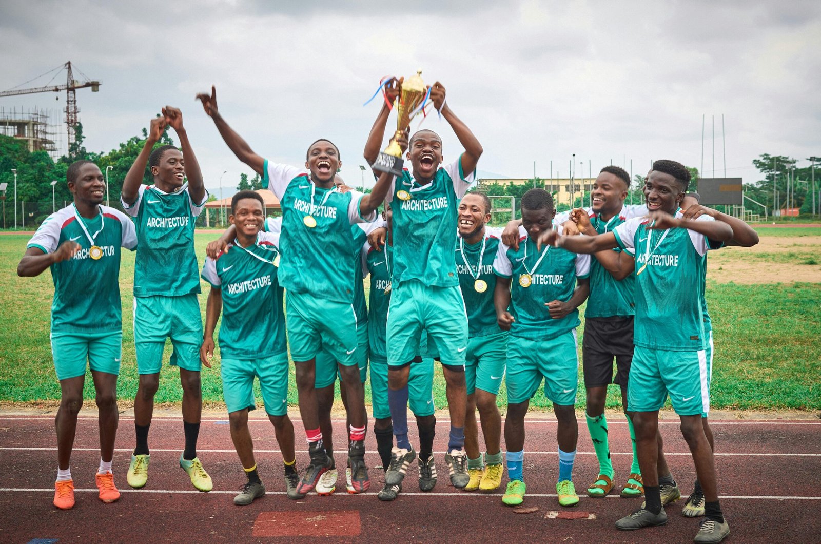 A joyous soccer team celebrating their victory with a trophy on the athletic field.